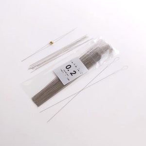 May include: A package of 0.2 mm silver wire for jewelry making. The package contains a variety of lengths of wire, including some with loops at the end. The wire is packaged in a clear plastic bag with a white label that says "0.2 mm wire".