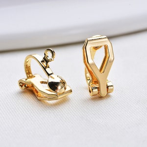 May include: Two gold-tone earring clips. The clips are designed to hold earrings in place. The clips are made of metal and have a smooth finish.