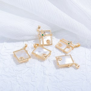 May include: Six gold-tone pendants shaped like gift boxes with white mother-of-pearl inlays and clear and green rhinestones.