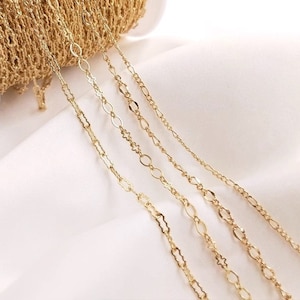 May include: Four gold chains of different styles and sizes lie on a white surface. The chains are all made of a fine, delicate metal.