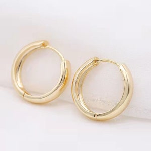 May include: A pair of gold hoop earrings. The earrings are simple and classic, with a smooth, polished finish.