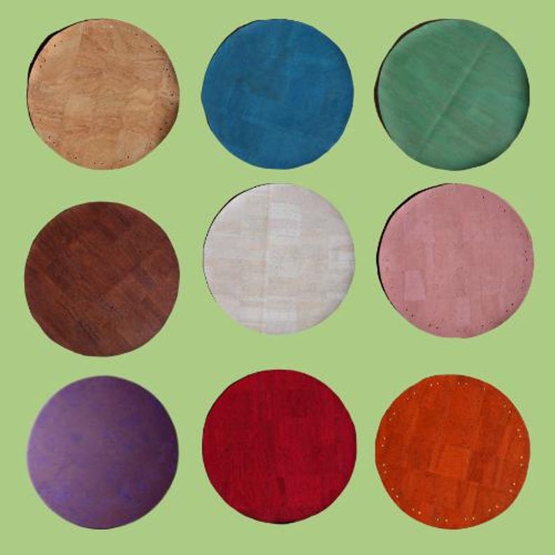 May include: Nine circular cork coasters in a variety of colours: natural, blue, green, brown, white, pink, purple, red, and orange. Each coaster has a textured surface and a stitched edge, ideal for protecting surfaces from drink rings.