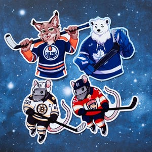 May include: Four die-cut stickers featuring cartoon animals in hockey jerseys. A bobcat in an Oilers jersey, a polar bear in a Maple Leafs jersey, and two mice in Bruins and Panthers jerseys, all holding hockey sticks.