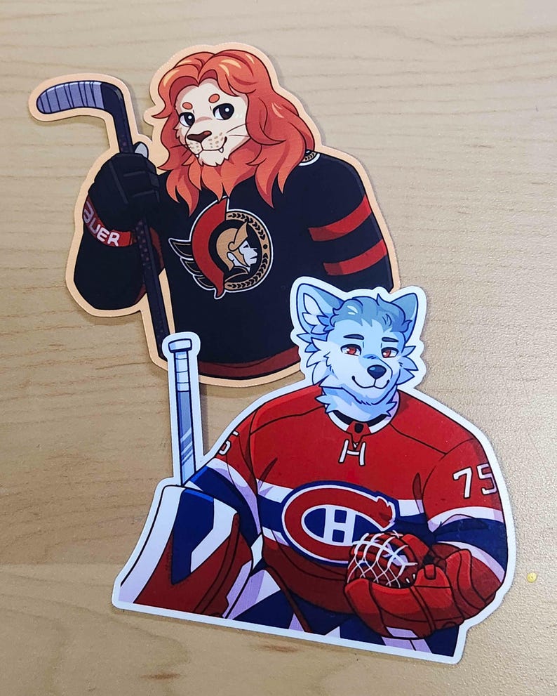 May include: Two stickers featuring anthropomorphic animals in hockey jerseys. One sticker shows a lion in a black jersey with red stripes, holding a hockey stick. The other sticker depicts a blue-furred wolf in a red jersey with a hockey glove.