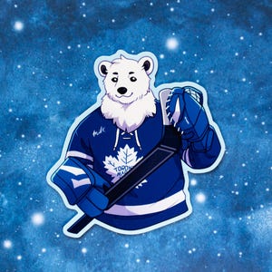 May include: A sticker featuring a cartoon polar bear wearing a blue hockey jersey with a white maple leaf logo. The bear is holding a hockey stick and wearing blue gloves. The background is a blue gradient with white stars.