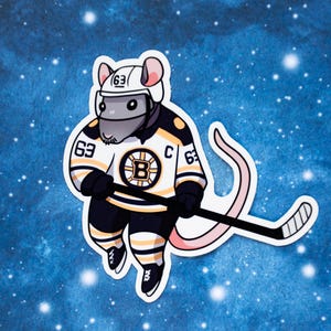 May include: A sticker featuring a cartoon rat in a hockey uniform. The rat wears a white helmet and a black, gold, and white jersey with the number 63 and a "B" logo. It holds a hockey stick against a blue background.
