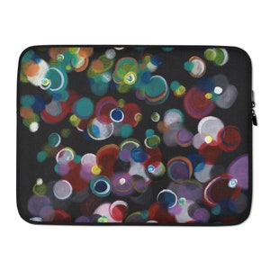 以下が含まれることがあります： 黒いラップトップスリーブ。赤、青、緑、紫、白の色合いで、重なり合う円のカラフルな抽象的なデザインが特徴です。円は柔らかくぼやけた外観で、奥行きと動きを感じさせます。黒いジッパーが上端に沿って走っています。