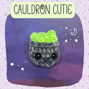 Puede incluir: Un caldero gris con una parte superior verde y ojos negros. El caldero es un juguete de peluche con una expresión linda. El fondo es un degradado morado con estrellas blancas.