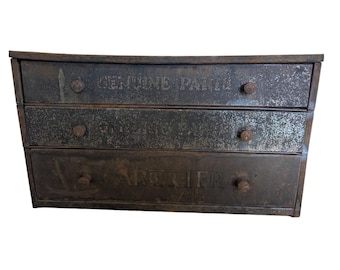 Cofre de piezas de metal vintage con tres cajones, divisores, piezas de carburador y letras antiguas.