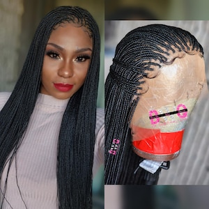 May include: A black braided wig with long, flowing strands. The wig features a natural-looking hairline and is styled with small, individual braids. The wig is shown on a mannequin head and on a person.