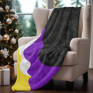 May include: A soft, plush throw blanket with a black, purple, white, and yellow design. The blanket is draped over a chair.