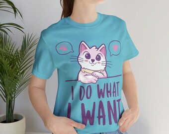 May include: A light blue t-shirt featuring a cartoon cat with the text "I DO WHAT I WANT". The cat is pink and white with a yellow collar. Speech bubbles with a paw print and a heart are above the cat.