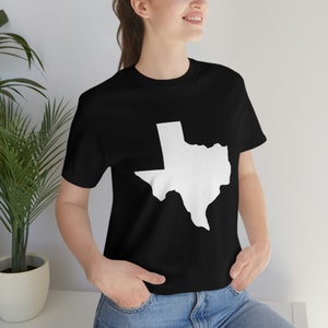 Może przedstawiać: Czarny T-shirt z białym obrysem stanu Teksas.