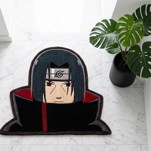 以下が含まれることがあります： 黒、赤、グレーの色使いのキャラクターデザインのラグ。ラグには、詳細な顔と服のデザインが施されています。白いタイルの床に置かれ、背景には鉢植えの植物があります。