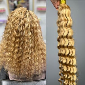 May include: Blonde human hair extensions with loose waves. The hair is a light blonde color with a few darker blonde highlights.