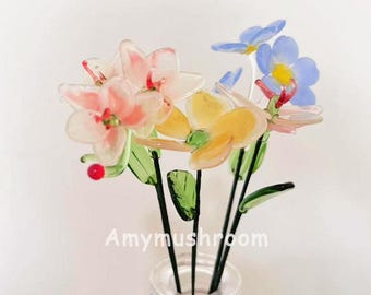 May include: A bouquet of glass flowers in a clear glass vase. The flowers are pink, yellow, and blue. The vase has a textured surface. The text "Amymushroom" is visible in the image.