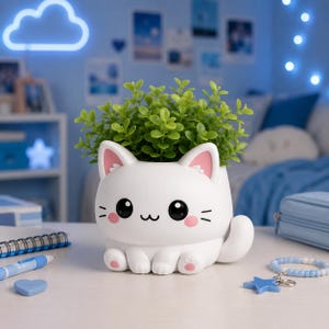 May include: A white cat-shaped planter with pink accents, holding a vibrant green plant. The planter features a cute design with black eyes, whiskers, and pink blush. The cat planter is a charming addition to any room.