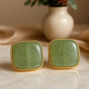 Puede incluir: Dos tiradores cuadrados de piedra verde con borde metálico dorado. Los tiradores tienen una superficie lisa y pulida. Los tiradores son un elemento decorativo de ferretería.