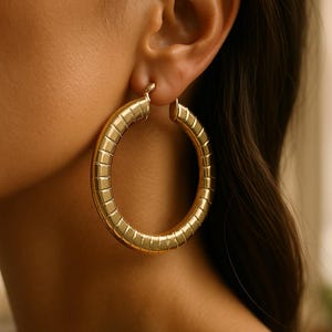 Brincos de argola dourados grandes e marcantes para o dia a dia, com textura clássica e redonda. Joias grandes e exuberantes.
