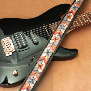 May include: A black electric guitar with a gold-colored bridge and a colorful patterned guitar strap.