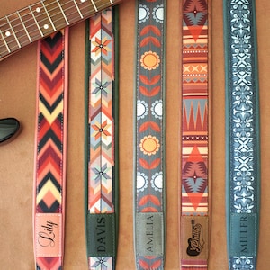 May include: Five guitar straps with different colorful patterns and names on the bottom. The names are Lily, Davis, Amelia, Philly, and Miller.