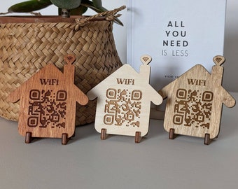 May include: Three wooden house-shaped signs with a QR code and the word "WIFI" on each. The signs are on a wooden surface.