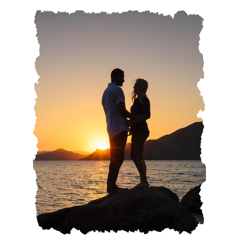 May include: Silhouette of a couple standing on a rocky shore at sunset. The couple is holding hands and looking at each other. The sun is setting in the distance, casting a warm glow over the scene.