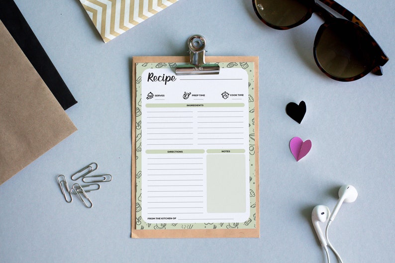 Puede incluir: Una plantilla de receta blanca con un borde verde y un respaldo de papel marr&oacute;n. La plantilla tiene secciones para "Sirve", "Tiempo de preparaci&oacute;n", "Tiempo de cocci&oacute;n", "Ingredientes", "Instrucciones" y "Notas". La plantilla est&aacute; en un portapapeles con un clip plateado.