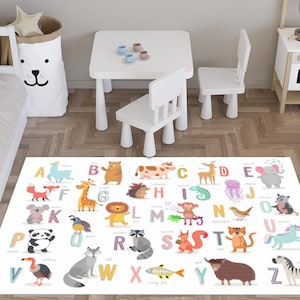 May include: A white rectangular rug with the alphabet and animal illustrations. The rug features colorful letters and cartoon animals like a giraffe, lion, and zebra. A white table and chairs are in the background.