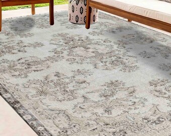 May include: A light grey area rug with a vintage floral pattern in shades of brown and grey. The rug is laid out on a patio with wooden furniture.