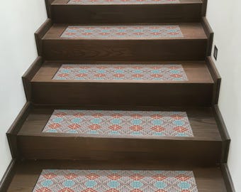 May include: Wooden staircase with patterned stair treads. The treads feature a repeating geometric design in red, blue, and gray. The stairs are made of dark brown wood.
