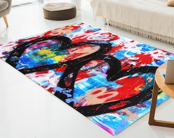 Pode incluir: Um tapete retangular com um design abstrato vibrante. Duas grandes formas de coração preto dominam o centro, contra um fundo de respingos de tinta vermelha, azul e branca. O tapete está colocado sobre um chão branco.