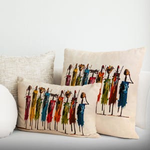 Peut inclure: Deux coussins décoratifs avec une peinture abstraite colorée d'un groupe de personnes portant des objets sur la tête. Le fond est de couleur beige clair.