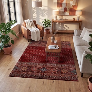 May include: A rectangular area rug featuring a deep red base color with intricate, repeating geometric patterns in shades of blue, orange, and cream, arranged in horizontal bands across the surface of the floor covering.