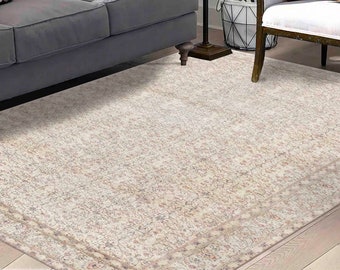 May include: A cream-coloured area rug with a subtle floral pattern and a border. The rug is laid out on a hardwood floor in a living room setting.
