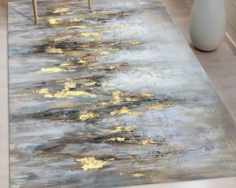 May include: Abstract area rug with a gray and white background and gold accents. The rug has a modern, contemporary design.