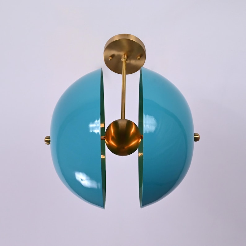 Op de afbeelding: Een tealblauwe, bolvormige plafondlamp met een messing centrum en twee helften die opengaan. De lamp wordt aan het plafond gehangen met een messing stang.