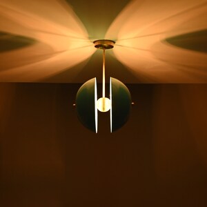Op de afbeelding: Een teal en witte bolvormige hanglamp met een enkele gloeilamp die aan het plafond hangt.