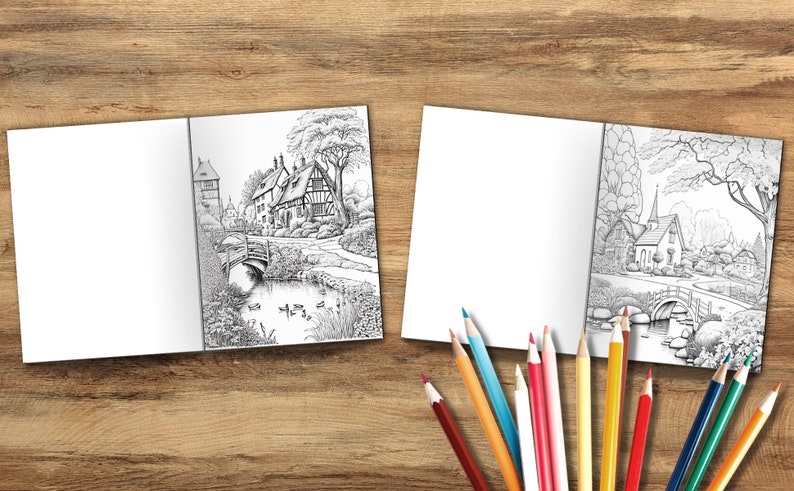 Puede incluir: Dos libros de colorear abiertos con ilustraciones en blanco y negro de un peque&ntilde;o pueblo con un puente y un estanque. Los libros est&aacute;n sobre una superficie de madera con l&aacute;pices de colores.