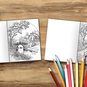 Puede incluir: Un libro de colorear abierto con dos ilustraciones en blanco y negro de una escena campestre con un puente, un r&iacute;o y casas. El libro est&aacute; sobre una superficie de madera con l&aacute;pices de colores.
