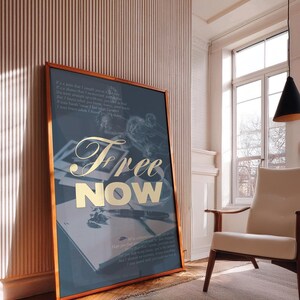 May include: A framed art print with a teal background and gold lettering that reads "Free NOW." The print features a vintage aesthetic with images of a pen, book, and other objects. The frame is a warm brown color.