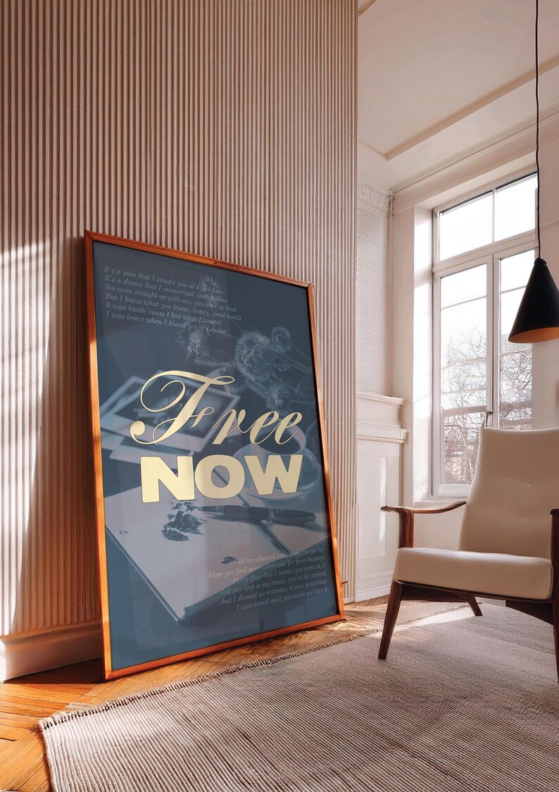 May include: A framed art print with a teal background and gold lettering that reads "Free NOW." The print features a vintage aesthetic with images of a pen, book, and other objects. The frame is a warm brown color.