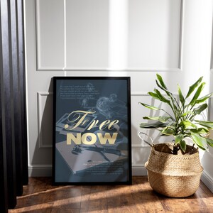May include: A framed art print with the words "Free Now" in gold lettering. The print is on a dark blue background with a faded illustration. A potted plant in a woven basket sits nearby.