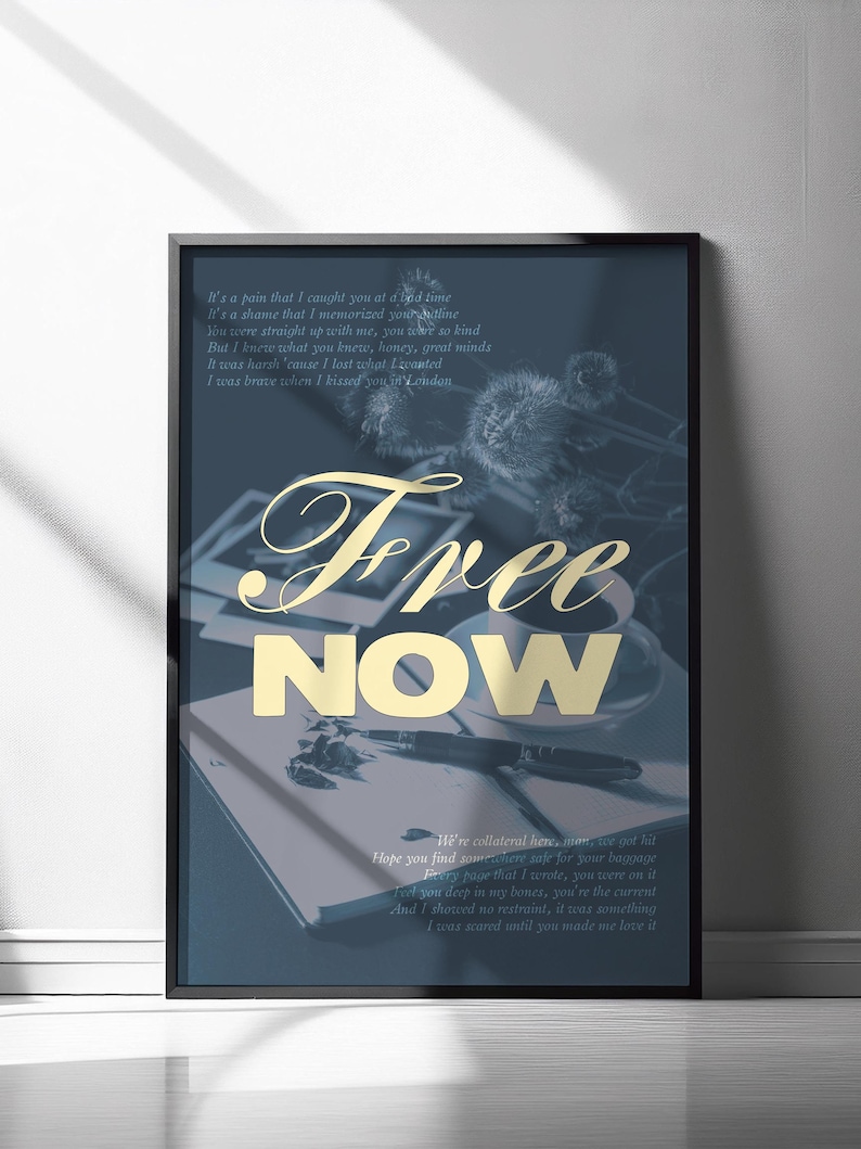 May include: A framed art print with a dark blue background and gold text that reads "Free Now." The print includes a poem and a photo of a cup, pen, and notebook. The artwork is displayed on a white wall.