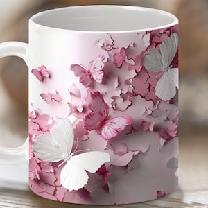 Può includere: Tazza in ceramica bianca con un design a farfalla rosa e bianca. Le farfalle sono sovrapposte su uno sfondo rosa con un effetto di vernice screpolata.