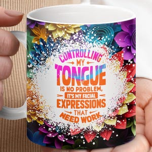 May include: White ceramic mug with a colorful floral design. The mug features a quote that reads "Controlling my tongue is no problem, it's my facial expressions that need work."