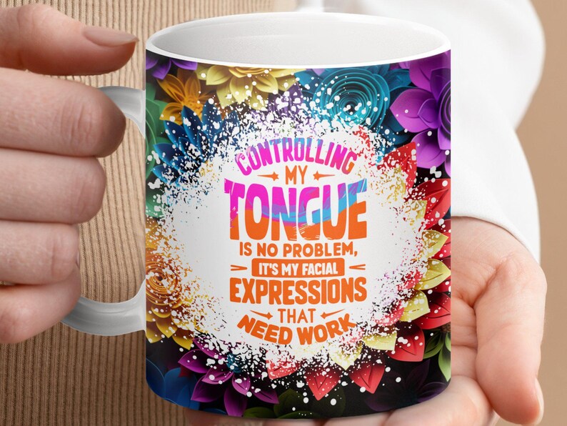 May include: White ceramic mug with a colorful floral design. The mug features a quote that reads "Controlling my tongue is no problem, it's my facial expressions that need work."