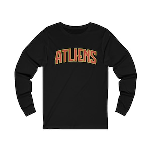 May include: Black long-sleeve t-shirt with the word "ATLIENS" in red and yellow lettering.