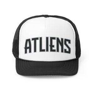 May include: A white and black trucker hat with a black mesh back. The front of the hat has the word "ATLIENS" in black with a gray outline.
