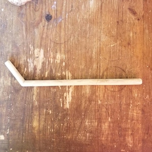 Könnte beinhalten: Ein einzelner, hellbrauner, Einweg-Trinkhalm auf einer Holzoberfläche.